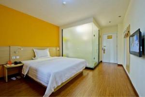 1 dormitorio con cama blanca y pared amarilla en 7Days Inn Ji`Nan Railway Station JingYi Road 4th en Jinan