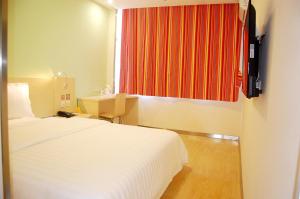 a hotel room with a bed and a red curtain at 7Days Inn Qinhuangdao Railway Station in Qinhuangdao