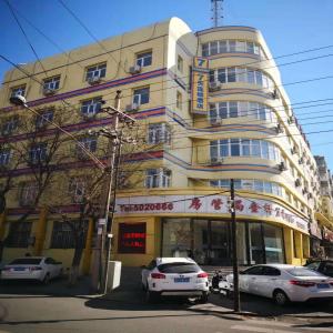 a building with cars parked in front of it at 7Days Inn Zhangjiakou Xuanhua Caishenmiao Street in Zhangjiakou