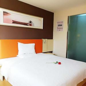 a bedroom with a white bed with a red rose on it at 7Days Inn Jinchang Culture Street in Jinchang