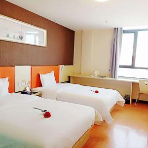 a hotel room with two beds with red roses on them at 7Days Inn Jinchang Culture Street in Jinchang