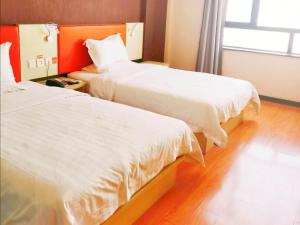 two beds in a hotel room with white sheets at 7Days Inn Jinchang Culture Street in Jinchang