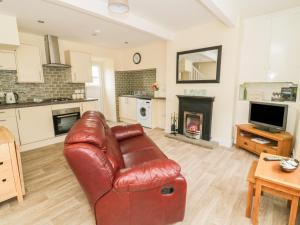 a living room with a leather couch and a fireplace at Wesley Cottage in Keighley