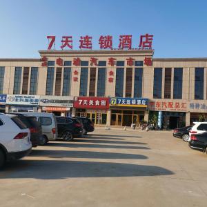 um grande edifício com carros estacionados em frente em 7Days Inn Guangrao Bus Terminal em Dongying