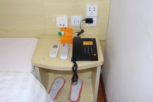 a telephone on a table next to a bed at 7Days Inn Bazhong International Trade City in Bazhong