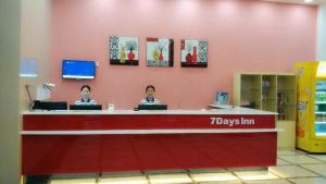 two people sitting at a counter in a store at 7Days Inn Bazhong International Trade City in Bazhong