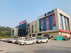 um parque de estacionamento com carros estacionados em frente a um edifício em 7Days Inn Bazhong International Trade City em Bazhong