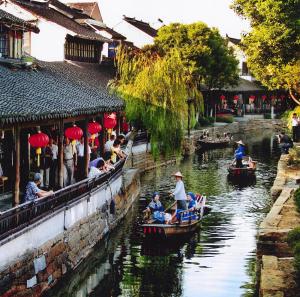 een groep mensen die in boten over een rivier varen bij 7Days Inn Suzhou Luzhi Ancient town in Dashi