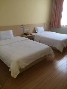 dos camas sentadas una al lado de la otra en una habitación en 7Days Inn Dezhou Qihe Coach College, en Dezhou