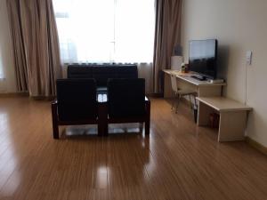 a room with two chairs and a table and a television at 7Days Inn Dezhou Qihe Coach College in Dezhou