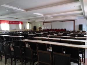 una sala de conferencias vacía con mesas y sillas en 7Days Inn Yulin Guangji building, en Yulin