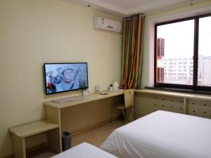 a bedroom with a desk with a television on it at 7Days Inn Yulin Guangji building in Yulin