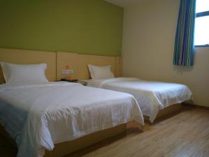 2 bedden in een hotelkamer met witte lakens bij 7Days Inn Shenzhen Shiyan in Longwancun