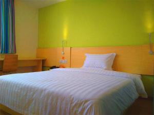 een slaapkamer met een wit bed en een groene muur bij 7Days Inn Shenzhen Shiyan in Longwancun