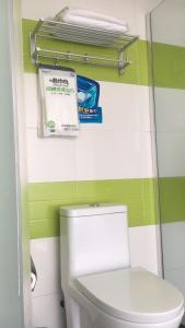 uma casa de banho com WC e uma parede verde e branca em 7Days Inn ChengDu RenShou Shuyuan Road Haochi Street em Meishan