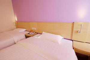 a hotel room with two beds and a phone at 7Days Inn ChengDu RenShou Shuyuan Road Haochi Street in Meishan