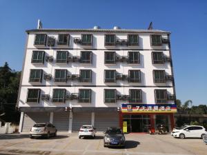 un gran edificio blanco con coches aparcados en un aparcamiento en 7Days Inn Shaoguan Renhua Mount Danxia en Shaoguan