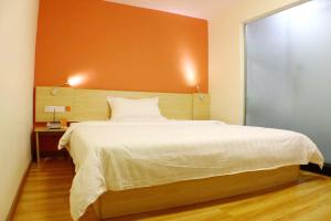 Un dormitorio con una cama grande con una pared naranja. en 7Days Inn Shaoguan Renhua Mount Danxia, en Shaoguan