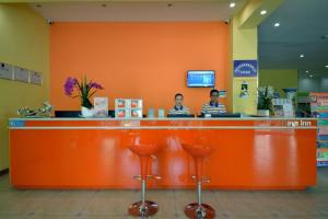 two men sitting at a orange counter in a store at 7Days Inn Xishuangbanna GaoZhuang West Shuangjing in Jinghong