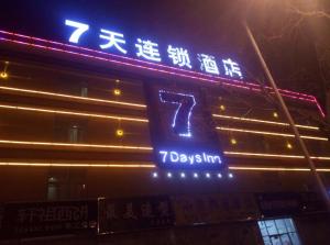 un panneau sur le côté d'un bâtiment la nuit dans l'établissement 7Days Inn Shangqiu democratic road WAL-MART, à Shangqiu