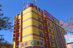 um edifício amarelo com sinais na lateral em 7Days Inn Hami Baofeng Market em Hami