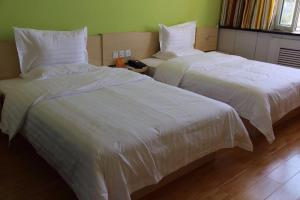 duas camas com lençóis brancos num quarto em 7Days Inn Hami Baofeng Market em Hami