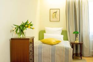 Un dormitorio con una cama y un jarrón de flores en un tocador en Hotel Krone Laupheim, en Laupheim