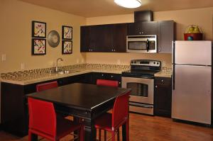 a kitchen with a black table and a white refrigerator at Oxford Suites Portland - Jantzen Beach in Portland