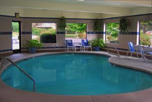 a large swimming pool with chairs and a table at Oxford Suites Portland - Jantzen Beach in Portland