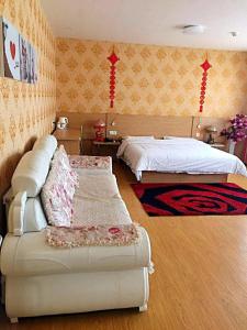 a bedroom with a bed and a couch in it at 7Days Inn Jixian County Road in Shuangyashan