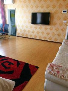 a living room with a couch and a flat screen tv at 7Days Inn Jixian County Road in Shuangyashan