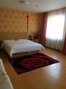 a bedroom with a bed and a rug on the floor at 7Days Inn Jixian County Road in Shuangyashan +3 photos
