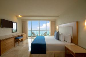 Grand Park Royal Cozumel - All Inclusive في كوزوميل: غرفة فندقية بسرير وإطلالة على المحيط