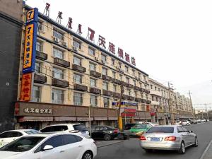 una strada con auto parcheggiate di fronte a un edificio di 7Days Inn Linhe Railway Station a Bayannur