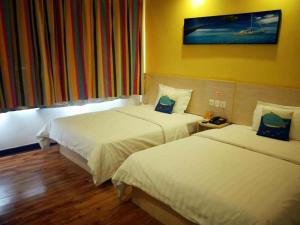 une chambre d'hôtel avec 2 lits et un tableau mural dans l'établissement 7Days Inn Linhe Railway Station, à Bayannuur