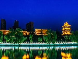 um edifício chinês com um reflexo na água à noite em 7Days Inn Weinan Jiefang Road railway station em Weinan
