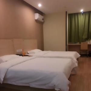 a room with three white beds and a window at 7Days Inn Dongtai Hong Lan Road RT-Mart in Dongtai