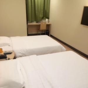 two beds in a hotel room with white sheets at 7Days Inn Dongtai Hong Lan Road RT-Mart in Dongtai