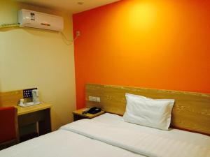 ein Schlafzimmer mit einem Bett mit einer orangefarbenen Wand in der Unterkunft 7Days Inn Chongqing Penghu Pengshui Garden in Pengshui