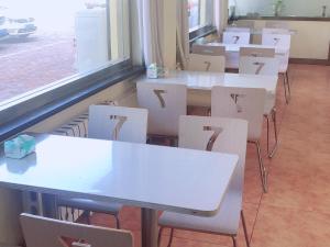 una fila de mesas y sillas blancas en un aula en 7Days Inn Dezhou Qihe Coach Terminal, en Huadian