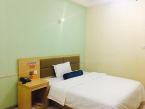 a bedroom with a white bed and a telephone at 7Days Inn Harbin Railway Station Zhanqian Square in Harbin