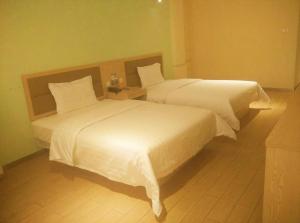 two beds in a hotel room with white sheets at 7Days Inn Harbin Railway Station Zhanqian Square in Harbin