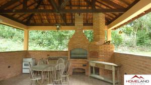 um pátio com um forno de tijolo, uma mesa e cadeiras em Alugo linda casa de campo perto de São Paulo com ótimo jardim, piscina e lareira. em Sará-Sará