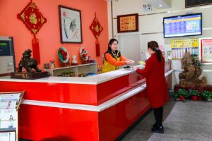 two women standing at a red counter in a store at 7Days Inn Longmen Grottoes of Luoyang Kaiyuan Avenue in Luoyang