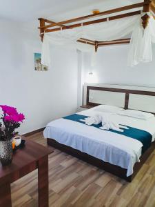 Schlafzimmer mit einem Bett mit weißer Bettwäsche und einem Tisch in der Unterkunft Casa Barina Costinești in Costinești