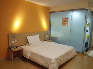 um quarto com uma cama branca e uma parede amarela em 7Days Inn Huaian vehicle administration em Huai'an