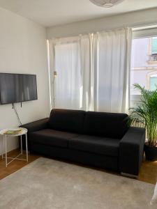 a black couch in a living room with a window at The Paquis Oasis in Central Geneva in Geneva