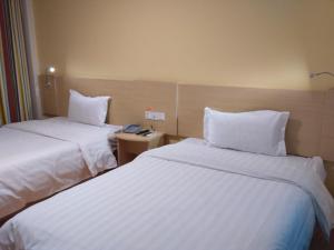 a hotel room with two beds with white sheets at 7Days Inn Kangding passenger terminal station in Garze