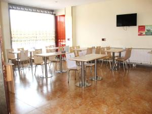 a dining room with tables and chairs and a flat screen tv at 7Days Inn Rizhao Development Zone in Rizhao