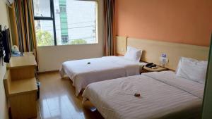 a hotel room with two beds and a window at 7Days Inn Yiyang victory road in Shangrao